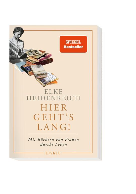 Cover von „Hier geht’s lang!“ von Elke Heidenreich: Eine Frau sitzt vor einem Stapel Bücher, in sanften Farben gehalten, mit dem Titel in großer Schrift.