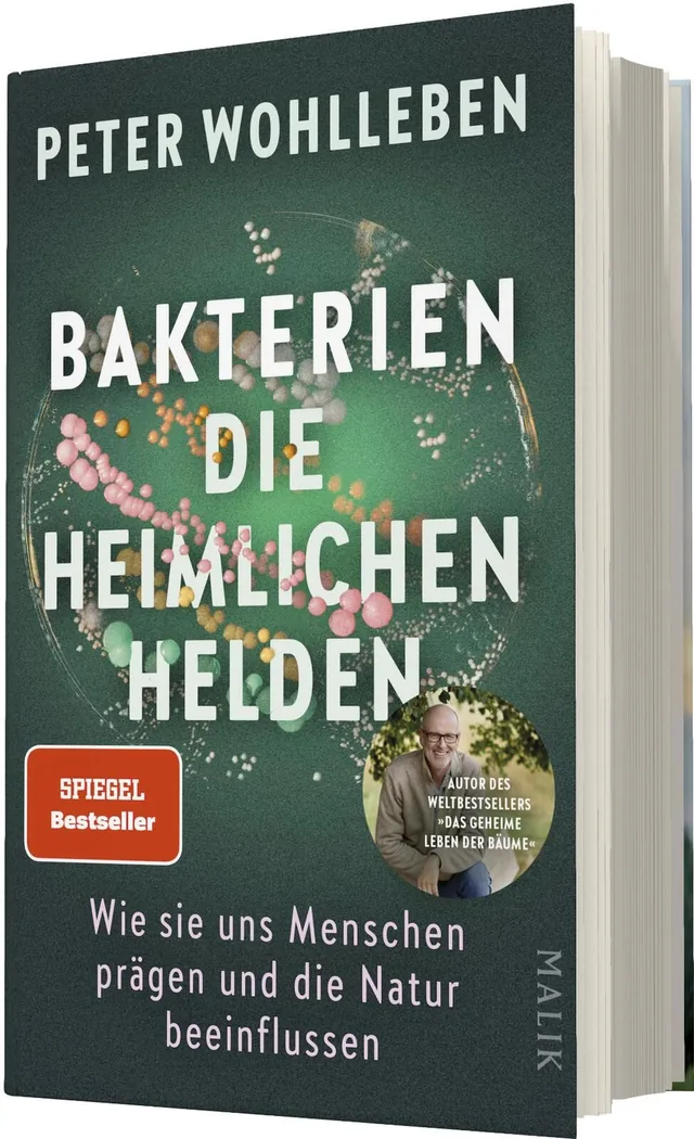 Das Buchcover zeigt einen grünen Hintergrund, auf dem bunte Bakterienstrukturen in verschiedenen Größen abgebildet sind. In großen, weißen Lettern steht der Titel „BAKTERIEN DIE HEIMLICHEN HELDEN“ zentral platziert. Darunter befindet sich der Untertitel „