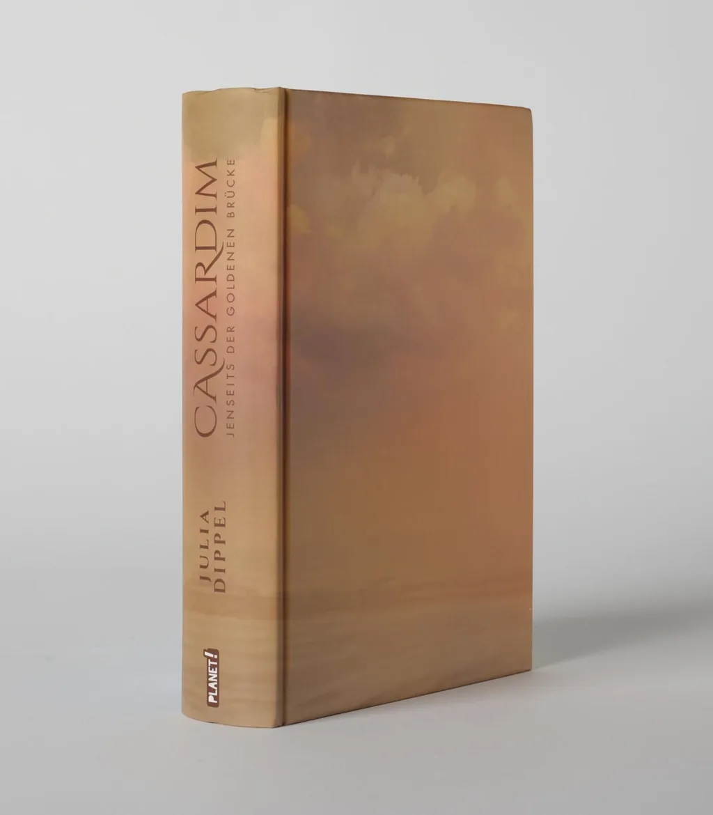 Das Buchcover zeigt eine sanfte, farbverlaufende Landschaft mit Wolken in Pastelltönen, die eine mystische Atmosphäre schaffen. Der Titel „Cassardim“ ist in auffälliger Schrift platziert.