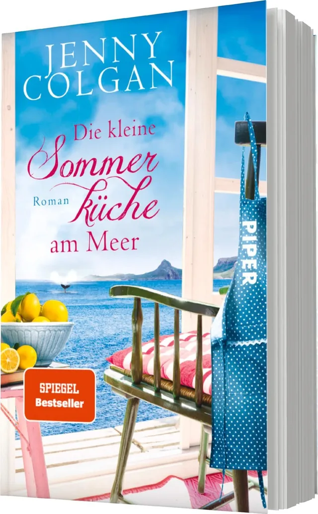 Das Buchcover zeigt einen hellen, einladenden Strandort mit Blick aufs Meer. Im Vordergrund steht ein Holztisch mit einer Schale Zitronen und einem bunten Kissen auf einer Holzbank. Die Farben sind freundlich und sommerlich, dominiert von Blau- und Rosatö