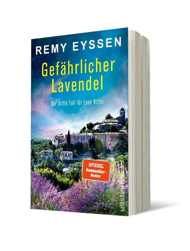 Cover von „Gefährlicher Lavendel“ von Remy Eyssen: Eine mediterrane Landschaft mit blühendem Lavendel im Vordergrund, im Hintergrund eine alte Stadt mit historischen Gebäuden, der Himmel strahlt in sanften Blau- und Mauvetönen.