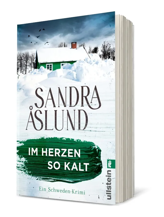 Cover von „Im Herzen so kalt“ von Sandra Åslund: Das Cover zeigt ein grünes Haus vor schneebedeckter Landschaft unter einem grauen Himmel, umgeben von Bäumen.