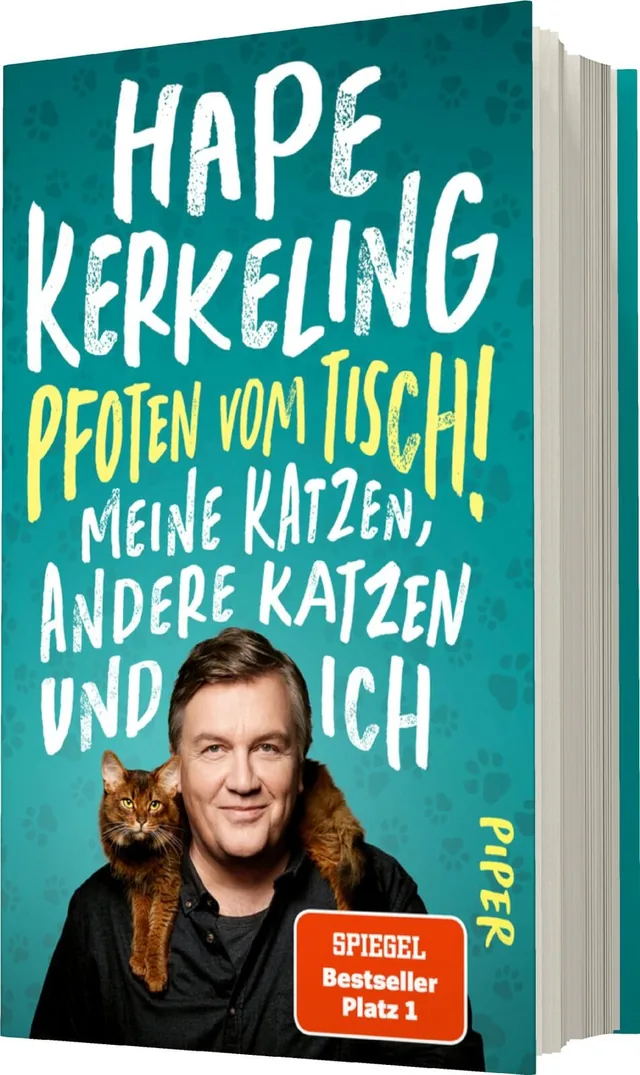 Das Buchcover zeigt Hape Kerkeling mit einem grinsenden Gesicht und einer Katze auf der Schulter. Der Hintergrund ist in einem lebendigen Türkis gestaltet, durchzogen von Pfotenabdrücken. Der Titel „Pfoten vom Tisch!“ ist in großer, verspielter weißer Sch